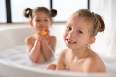 Photo of Cute little sisters taking bubble bath together