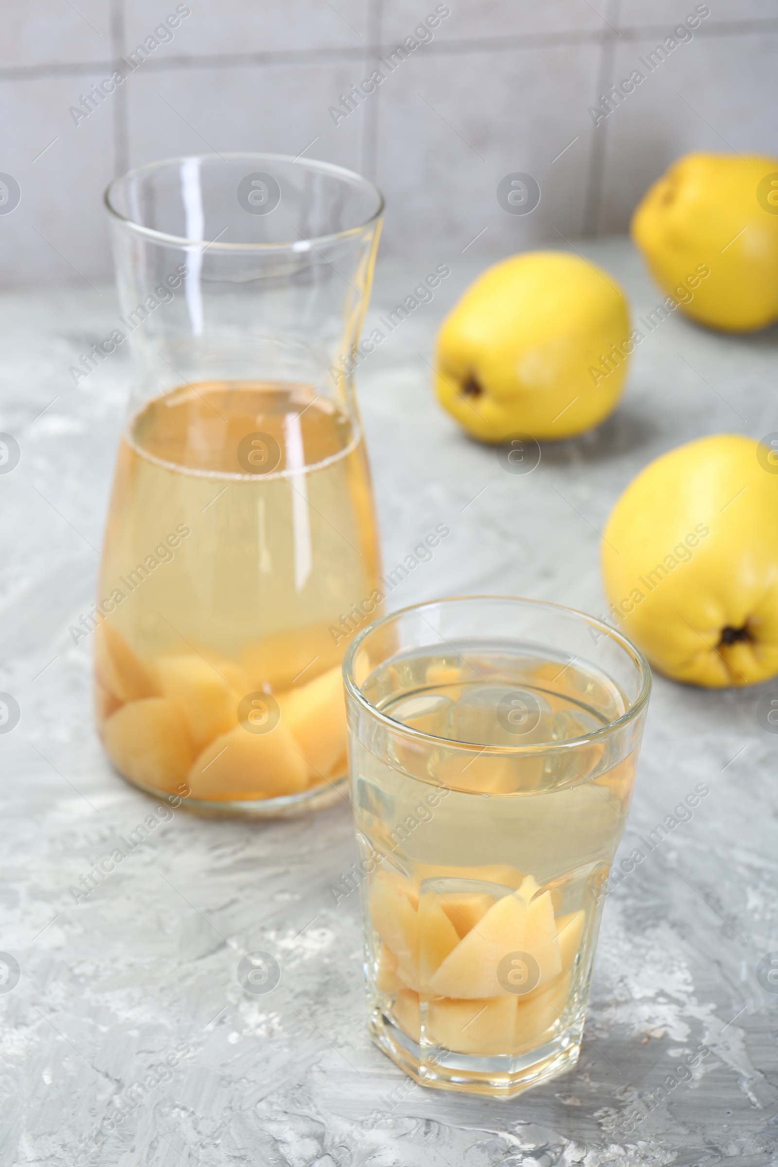 Photo of Delicious quince drink and fresh fruits on grey table