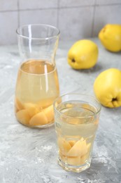 Photo of Delicious quince drink and fresh fruits on grey table