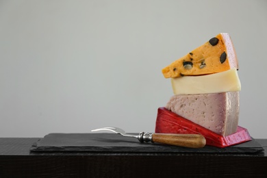 Different types of delicious cheeses and fork on slate plate. Space for text