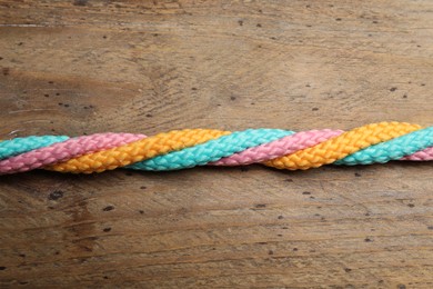 Photo of Twisted colorful ropes on wooden background, top view. Unity concept