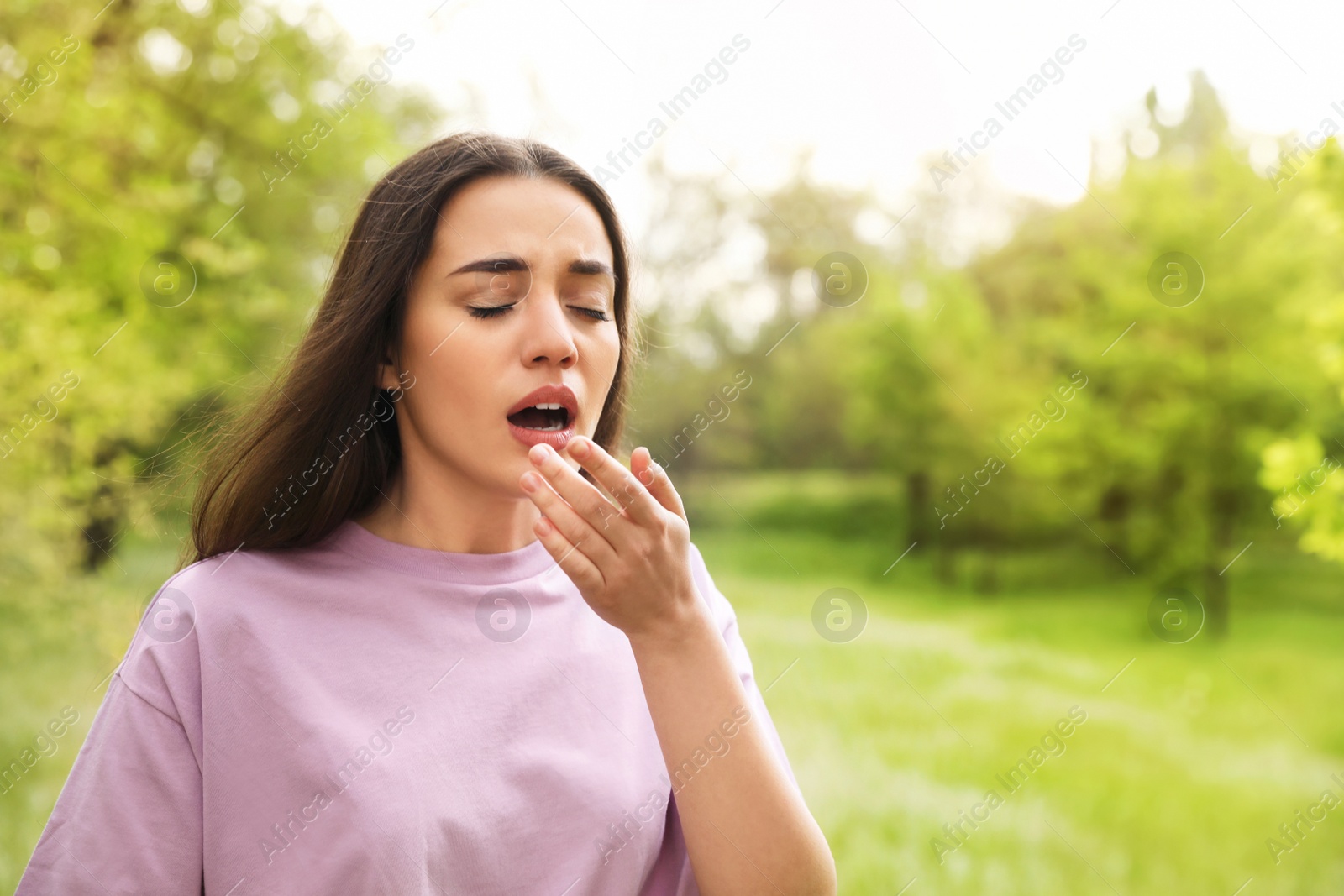 Photo of Young woman suffering from seasonal allergy outdoors, space for text