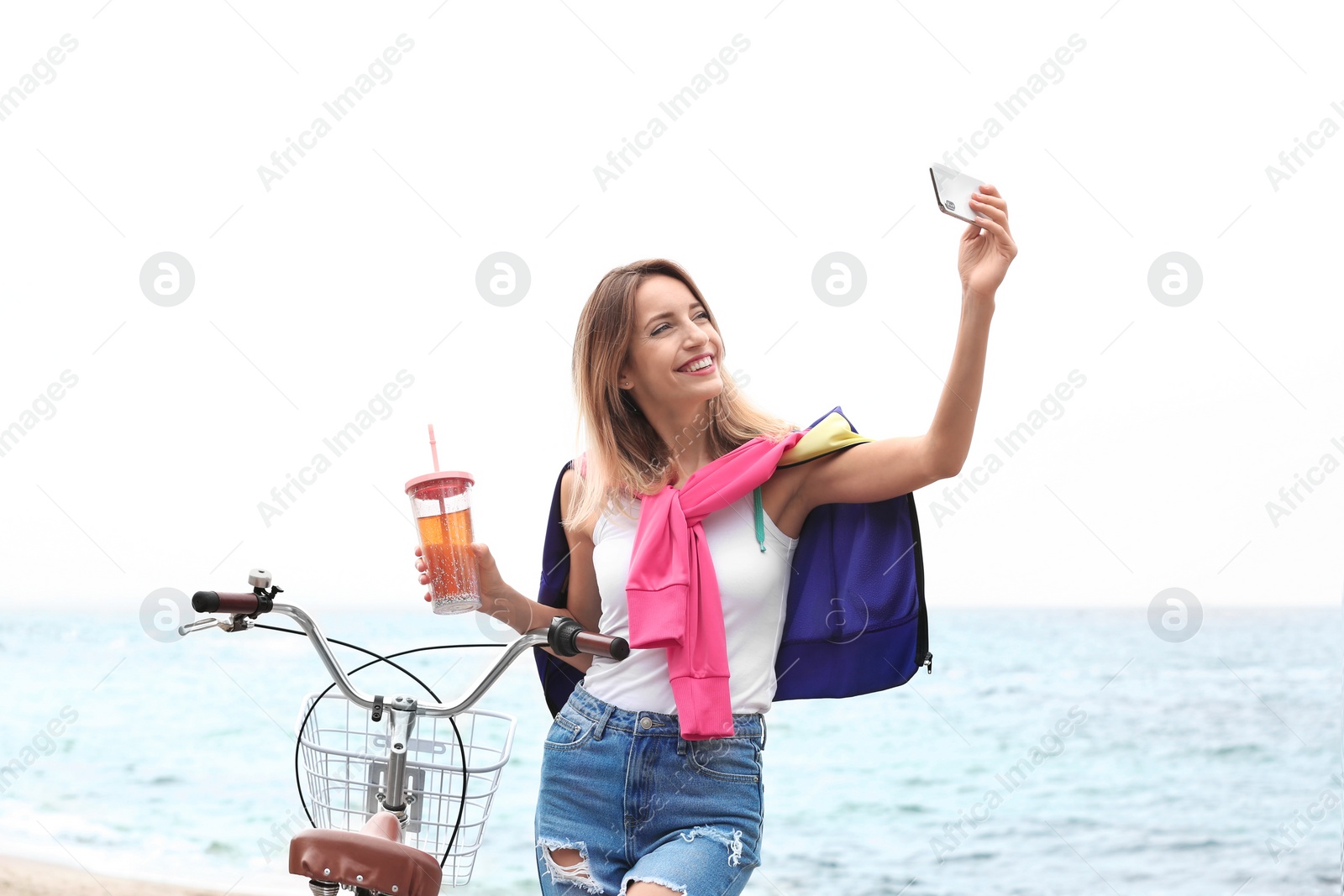 Photo of Attractive woman taking selfie near bicycle on sea coast