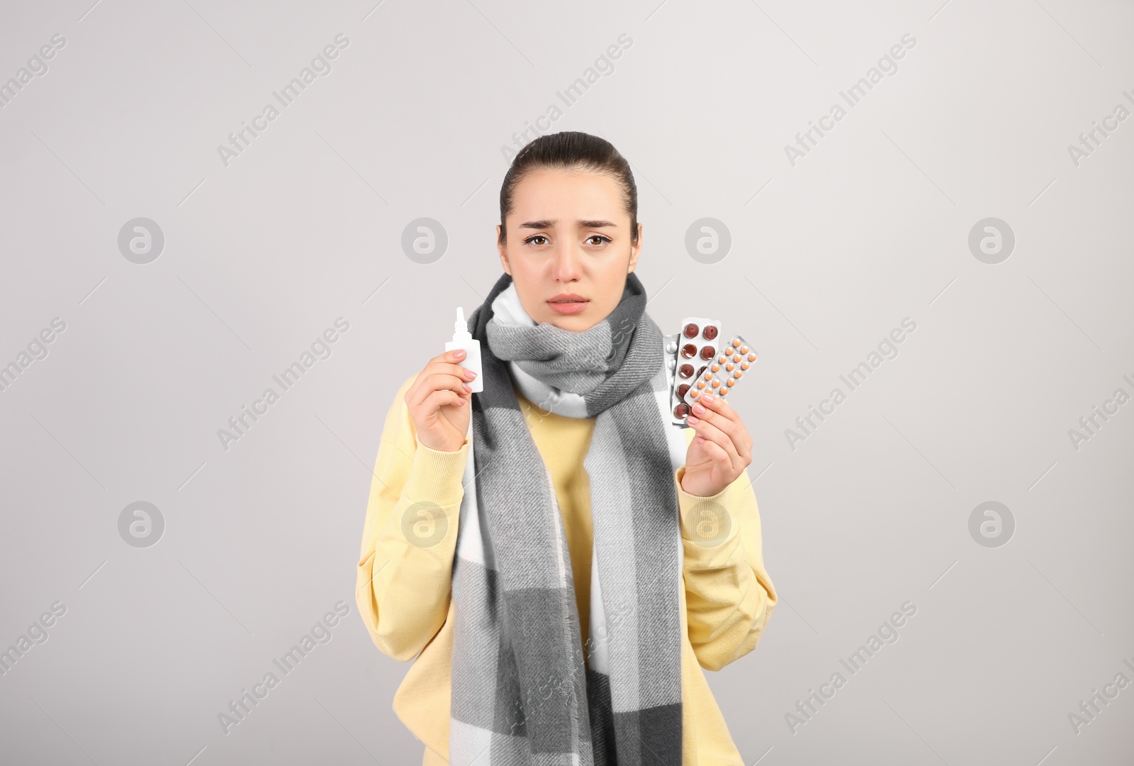 Photo of Woman with nasal spray and pills on light grey background