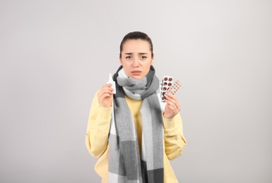 Photo of Woman with nasal spray and pills on light grey background