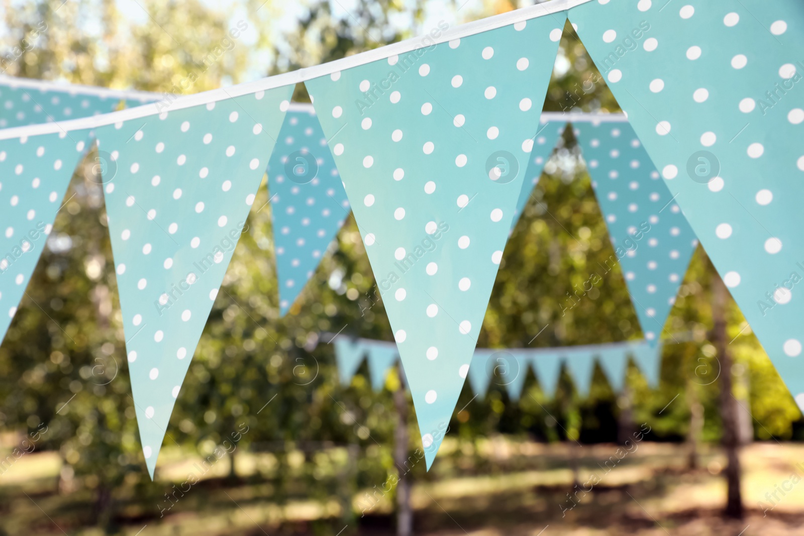 Photo of Light blue bunting flags in park. Party decor