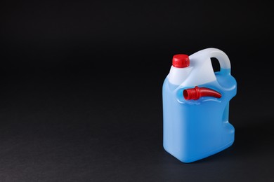 Plastic canister with blue liquid on black background. Space for text