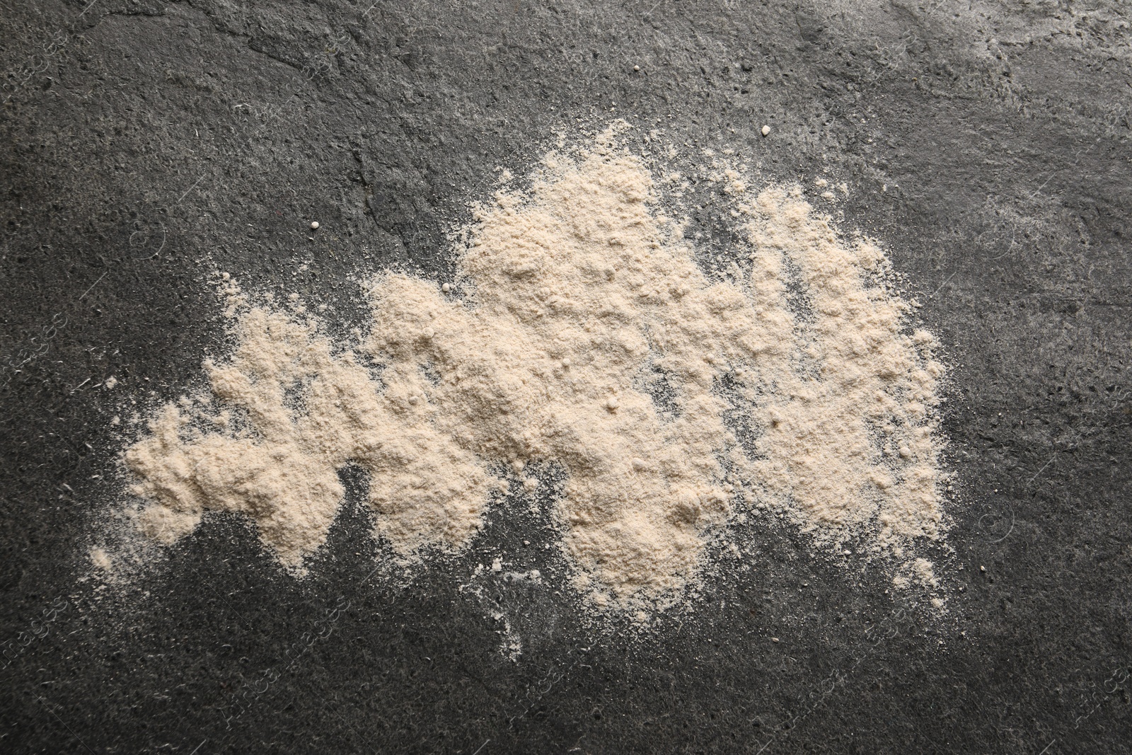 Photo of Scattered flour on grey textured table, top view