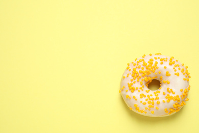 Delicious glazed donut on yellow background, top view. Space for text