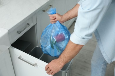 Photo of Man taking garbage bag out of bin at home, closeup