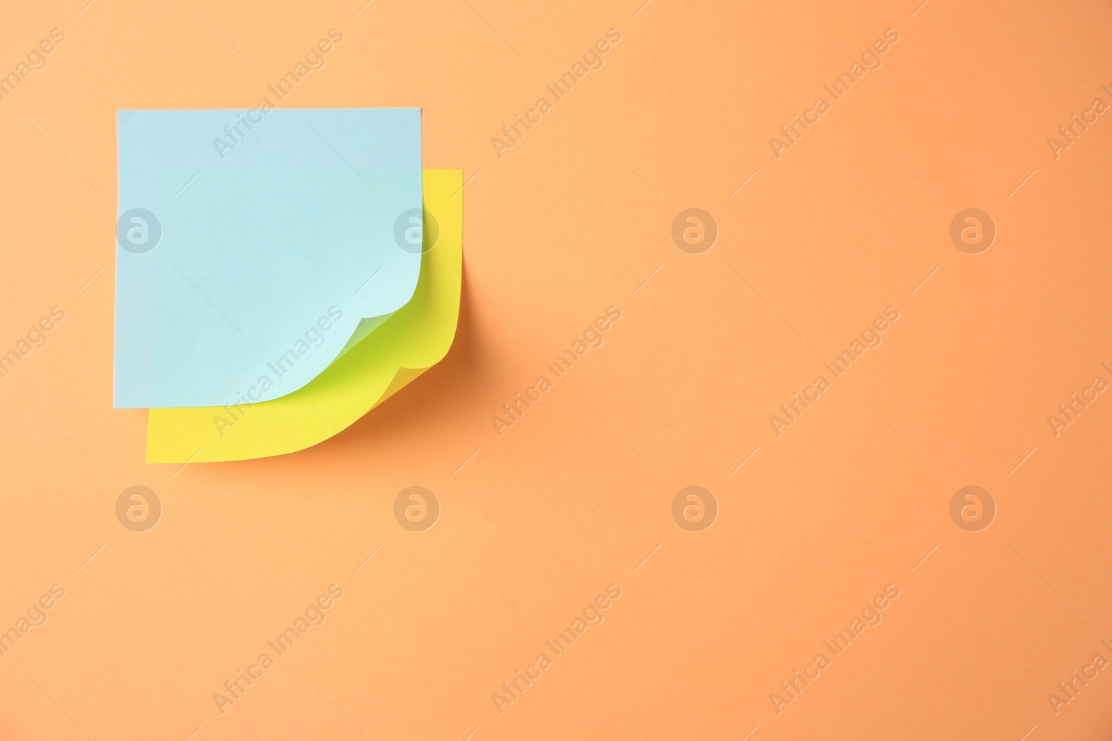 Photo of Blank paper notes on pale orange background, top view. Space for text