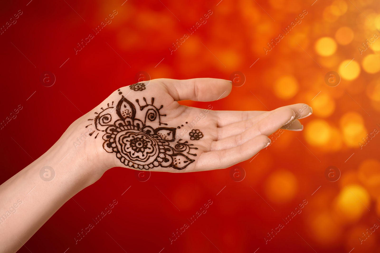 Image of Woman with henna tattoo on palm against blurred lights, bokeh effect