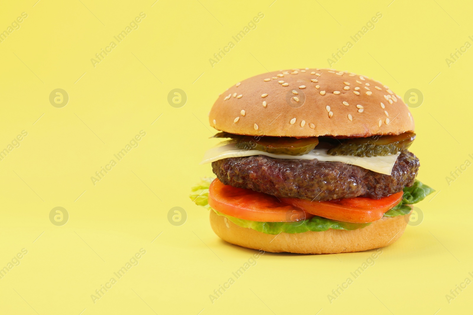 Photo of Burger with delicious patty on yellow background. Space for text