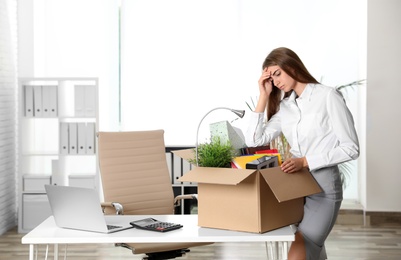 Upset young woman packing stuff in box at office