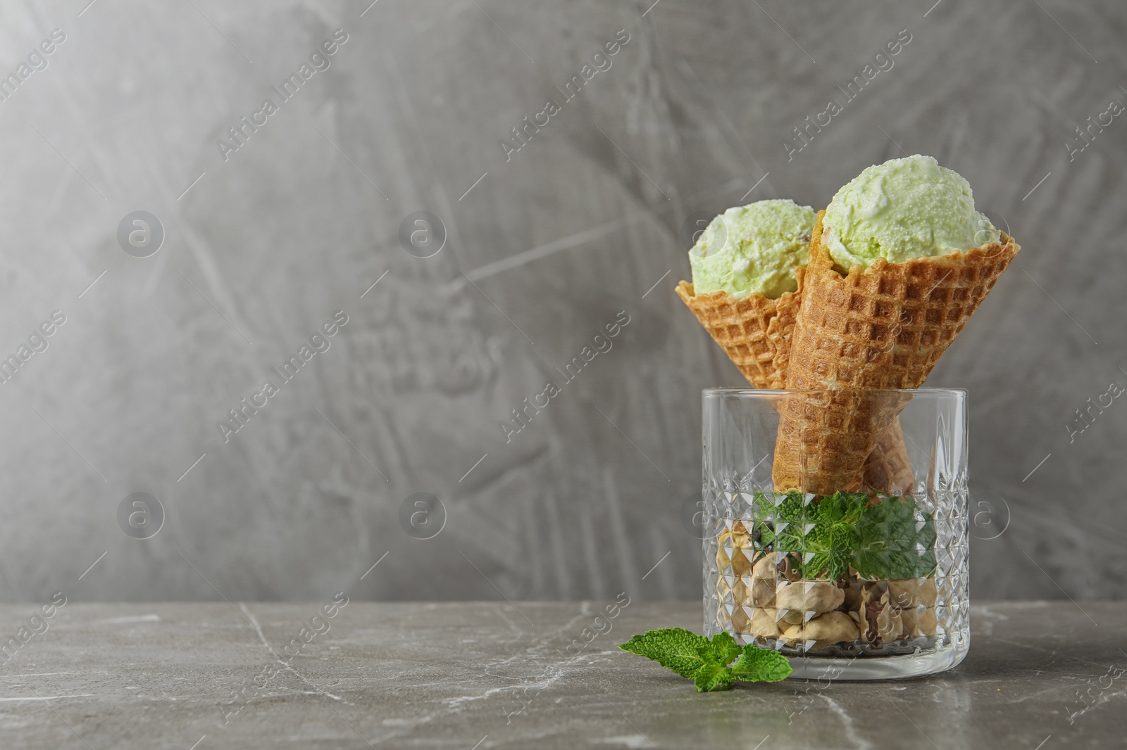 Photo of Delicious pistachio ice cream on grey marble table. Space for text