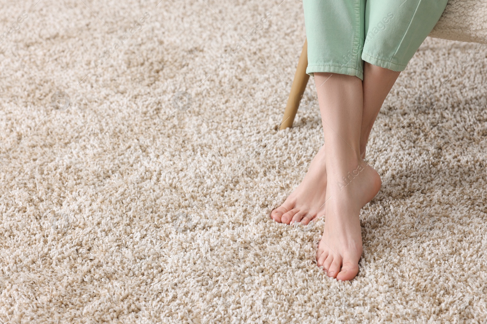 Photo of Woman on soft light brown carpet at home, closeup. Space for text