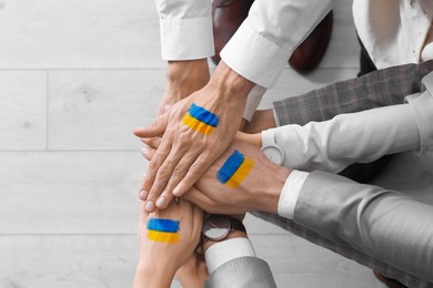 Image of United for Ukraine. People holding hands with drawings of Ukrainian flag together, closeup