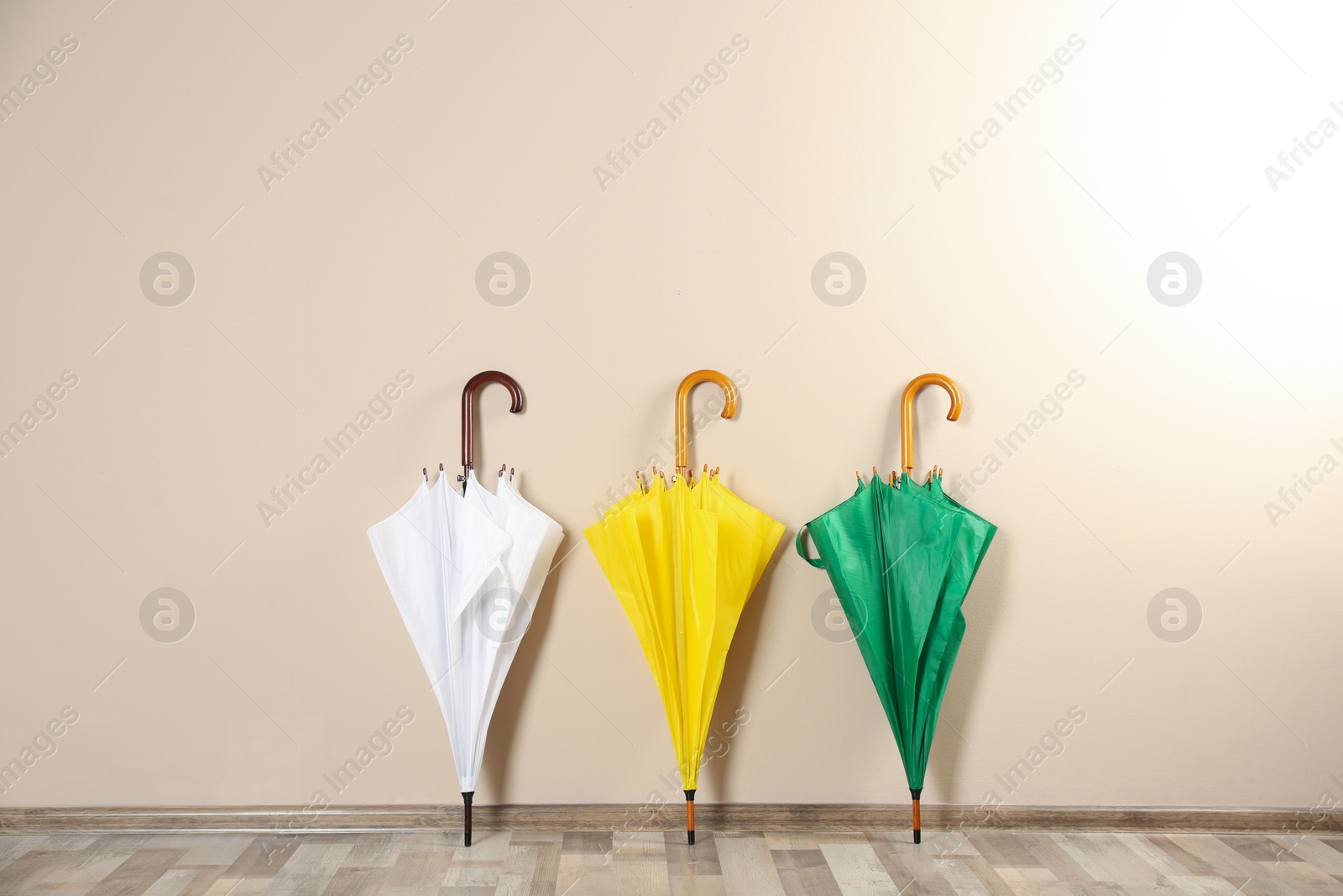 Photo of Beautiful closed colorful umbrellas near beige wall