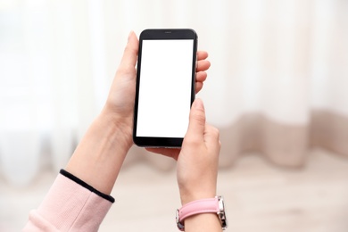 Photo of Woman holding smartphone with blank screen indoors, closeup of hands. Space for text