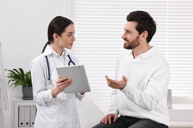 Doctor with tablet consulting patient during appointment in clinic