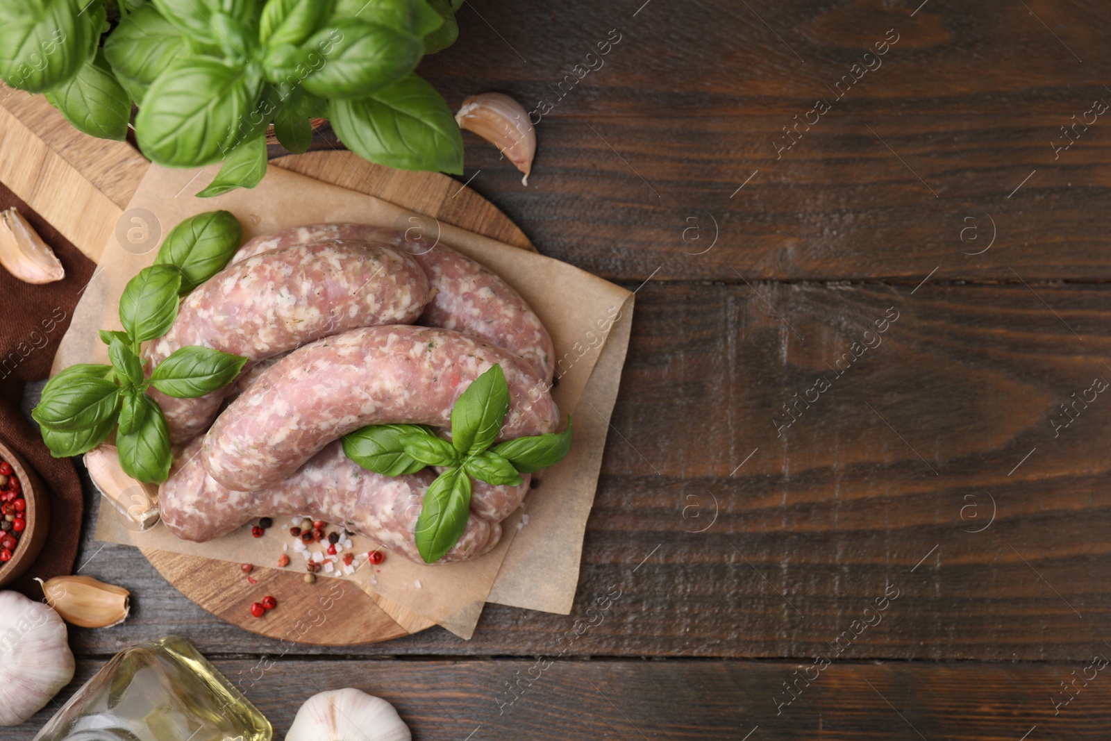 Photo of Raw homemade sausages and different products on wooden table, flat lay. Space for text