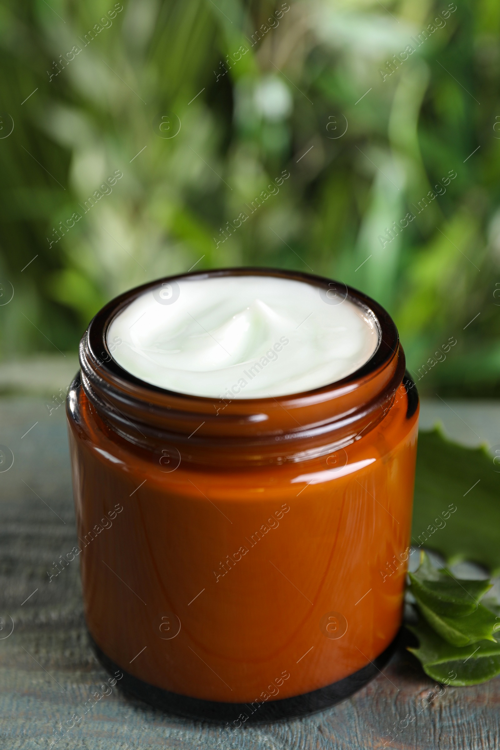 Photo of Jar of hand cream and aloe on light blue wooden table, closeup