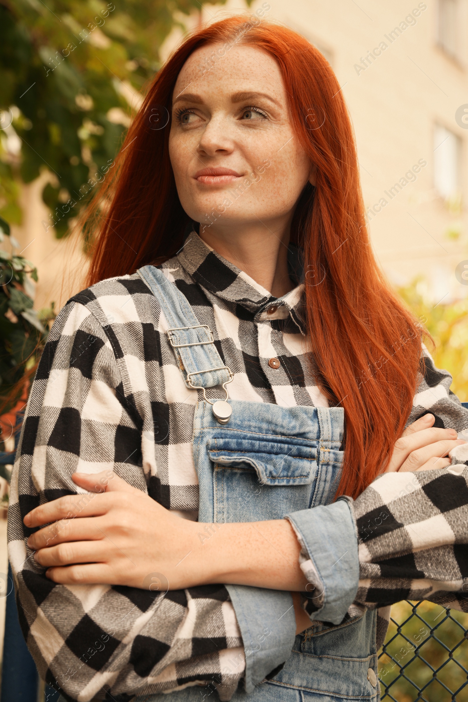 Photo of Portrait of beautiful young woman with red hair near fence outdoors