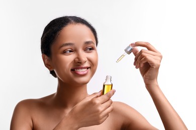 Smiling woman with bottle of serum and dropper on white background