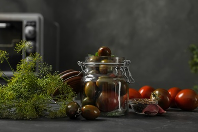 Photo of Pickling jar with fresh tomatoes on black kitchen table