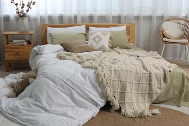 Photo of Large comfortable bed with soft pillows, duvet and blanket in room. Home textile