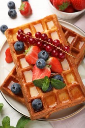 Photo of Delicious Belgian waffles with berries served on white table, top view