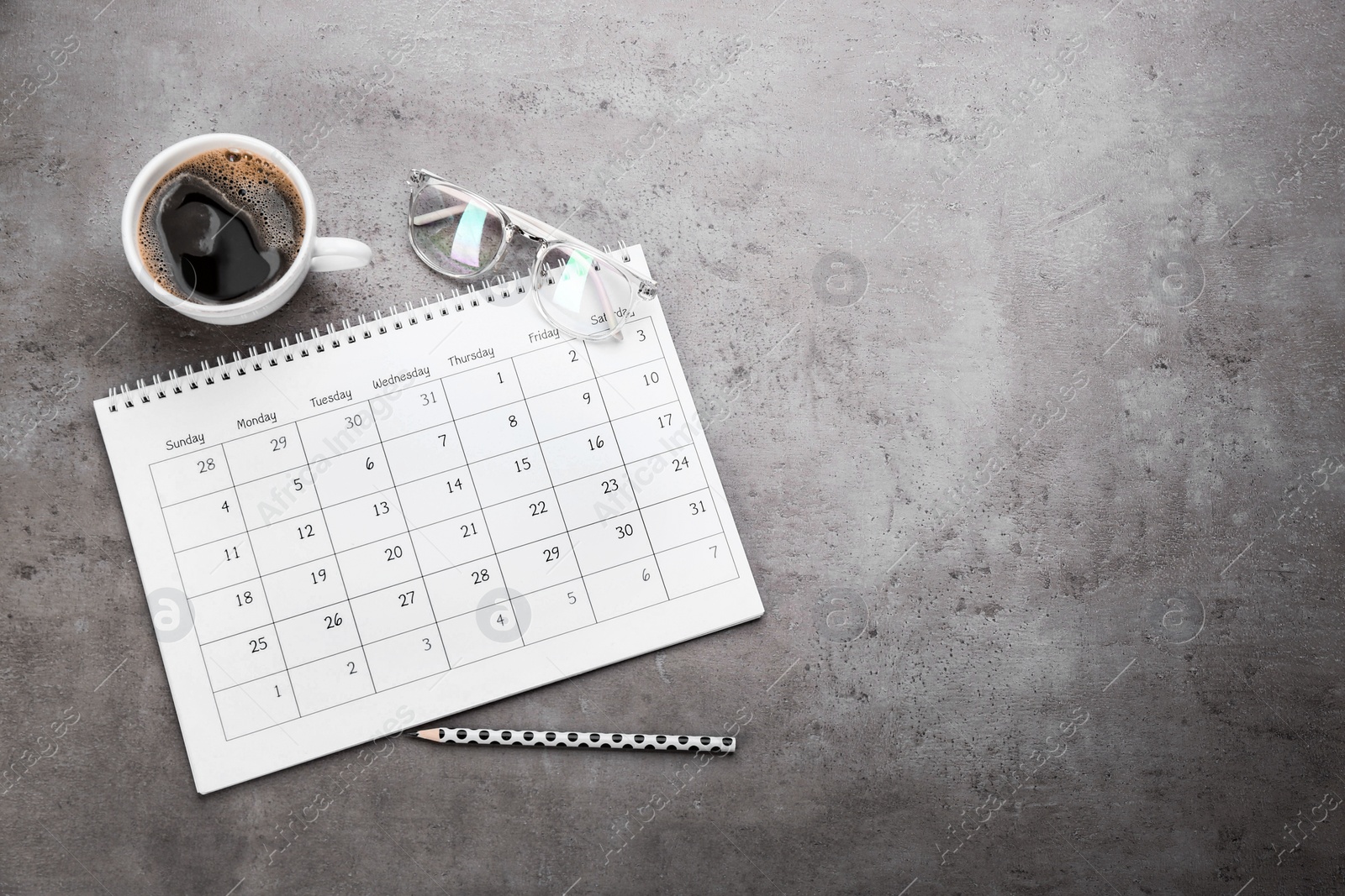 Photo of Flat lay composition with calendar and cup of coffee on grey stone table. Space for text