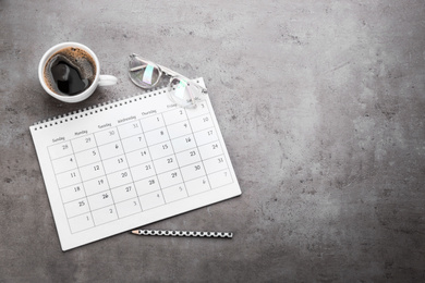 Flat lay composition with calendar and cup of coffee on grey stone table. Space for text