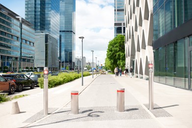 Photo of Beautiful bollards near buildings with many windows on cloudy day in city