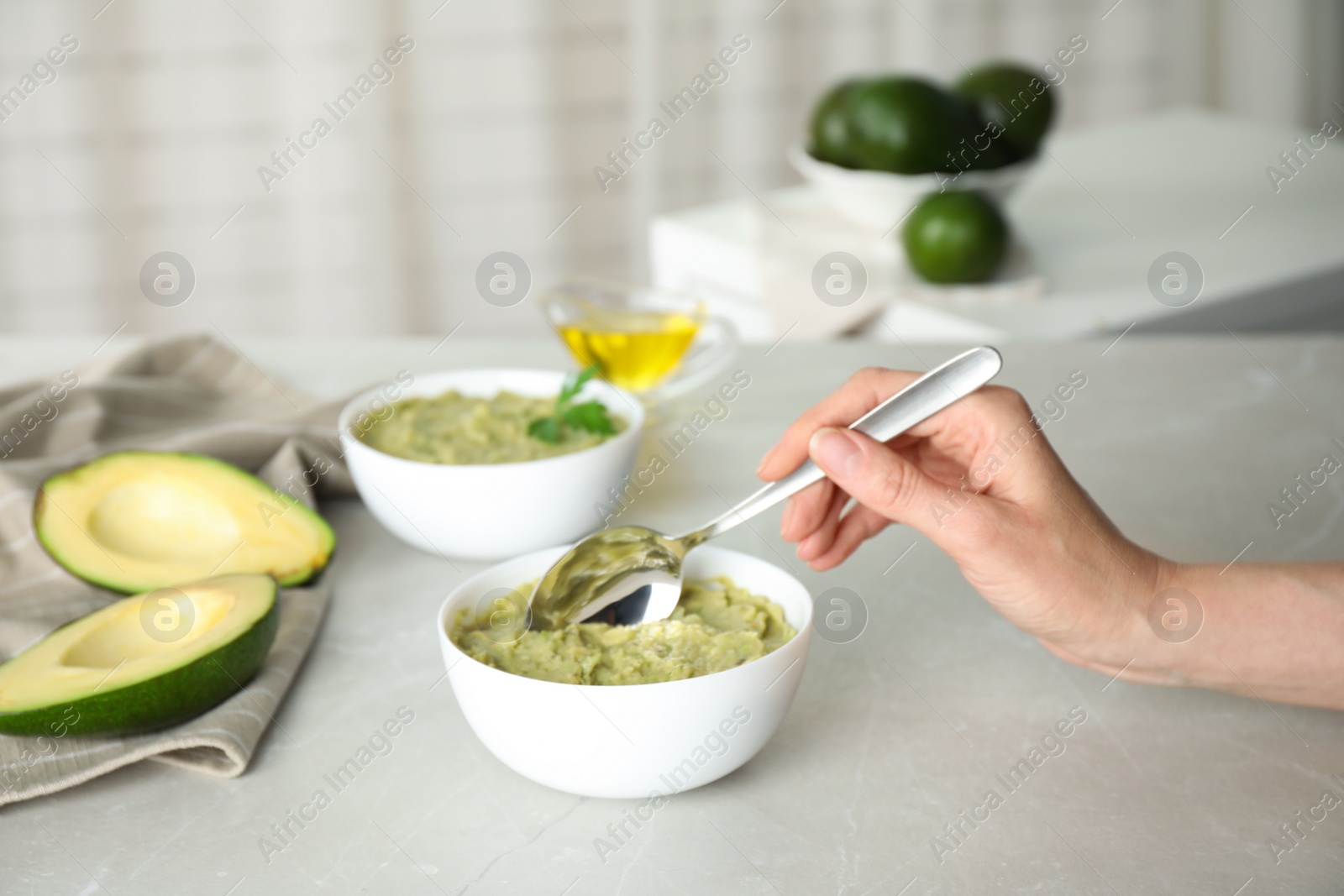 Photo of Woman preparing guacamole of ripe avocados at light table indoors, closeup. Space for text