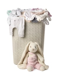 Photo of Laundry basket with baby clothes near soft toy isolated on white