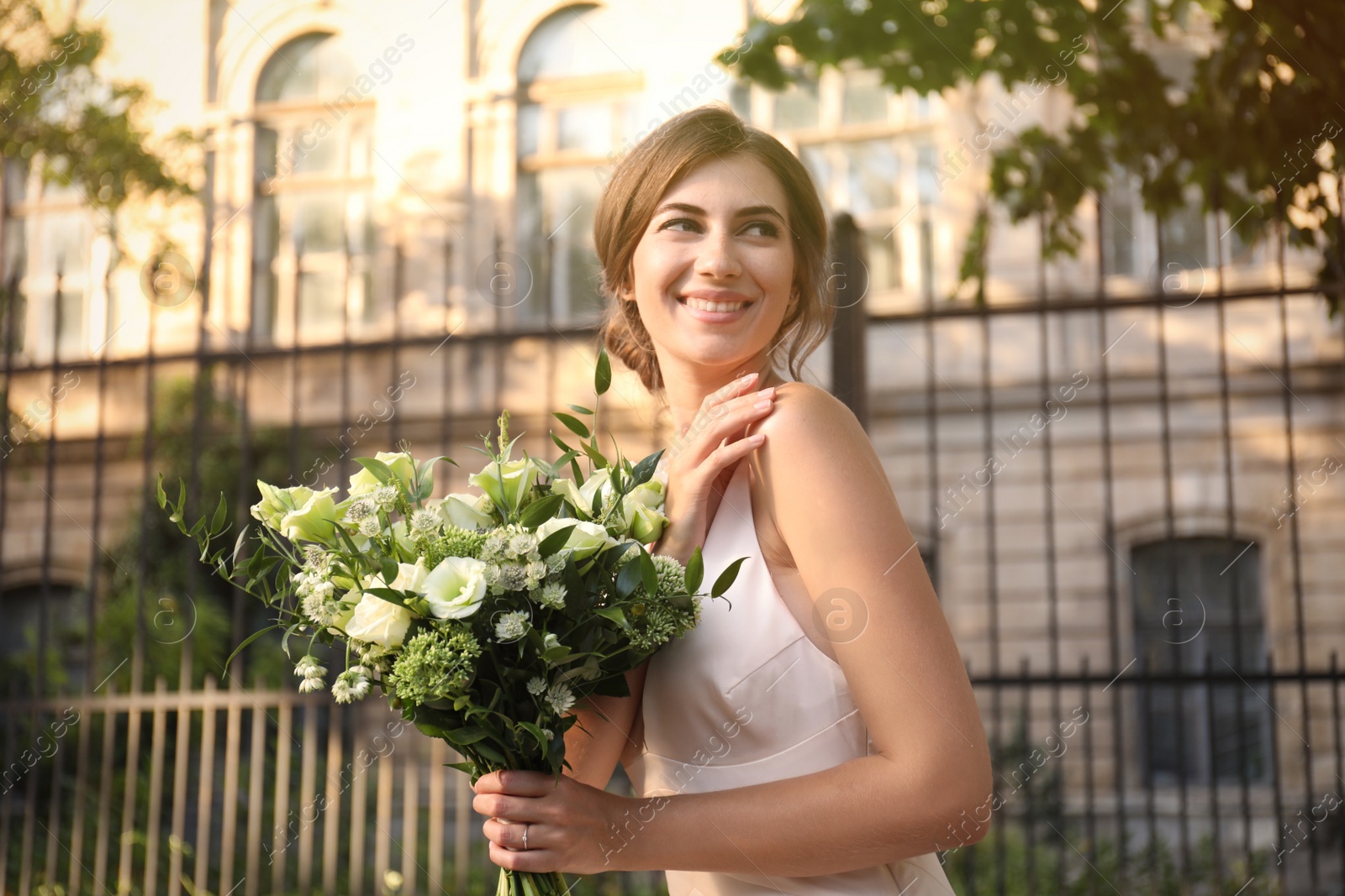 Photo of Gorgeous bride in beautiful wedding dress with bouquet outdoors