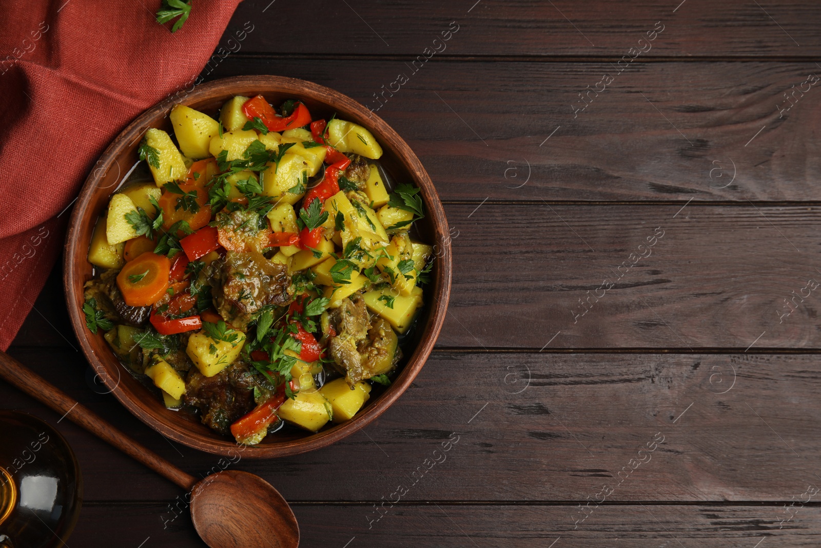 Photo of Tasty cooked dish with potatoes in earthenware served on wooden table, flat lay. Space for text