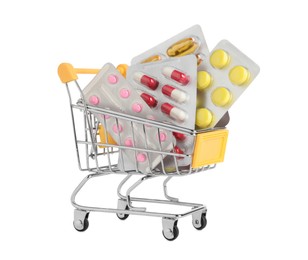 Blisters with different pills in mini shopping cart on white background