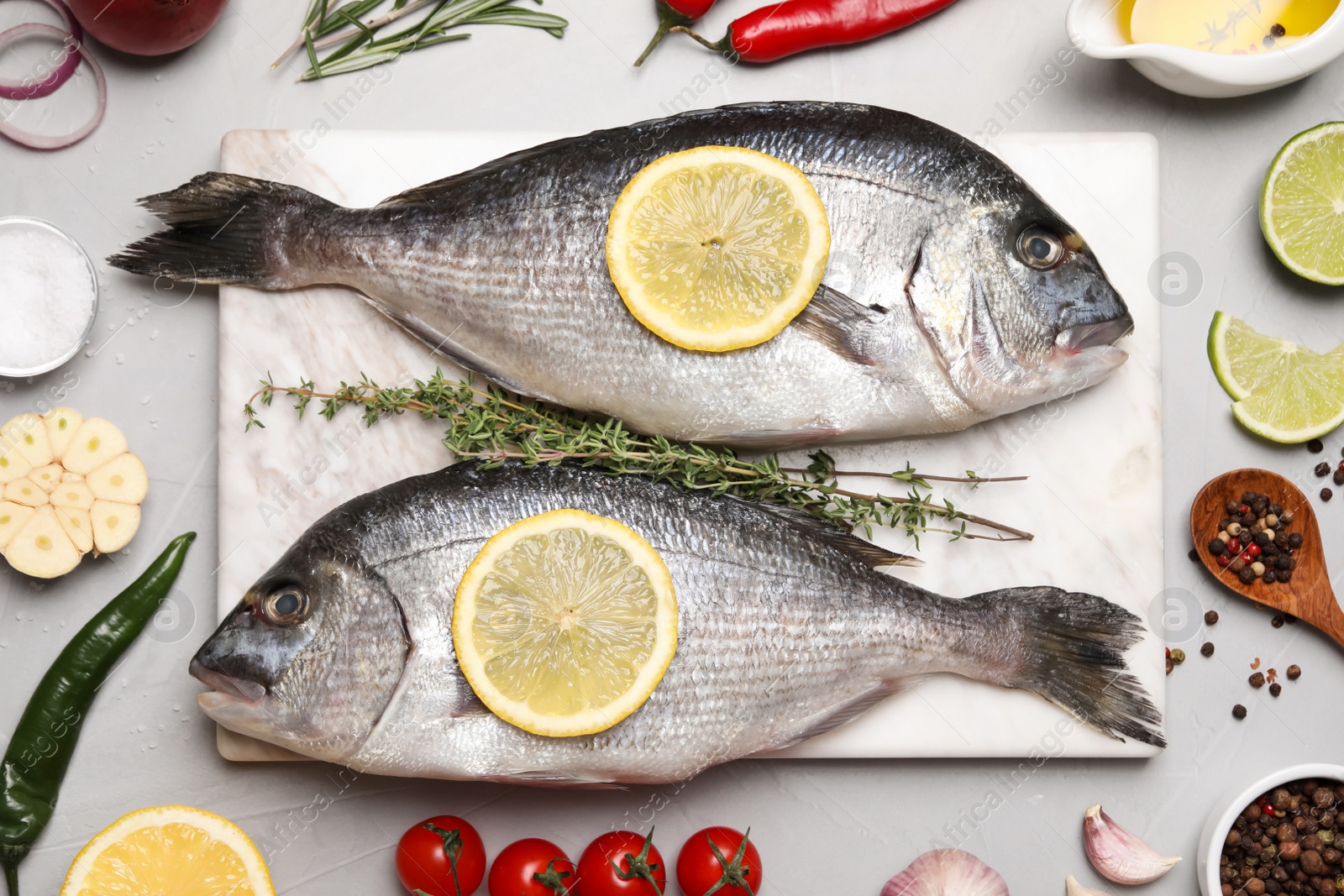 Photo of Flat lay composition with fresh raw dorado fish and ingredients on light grey table