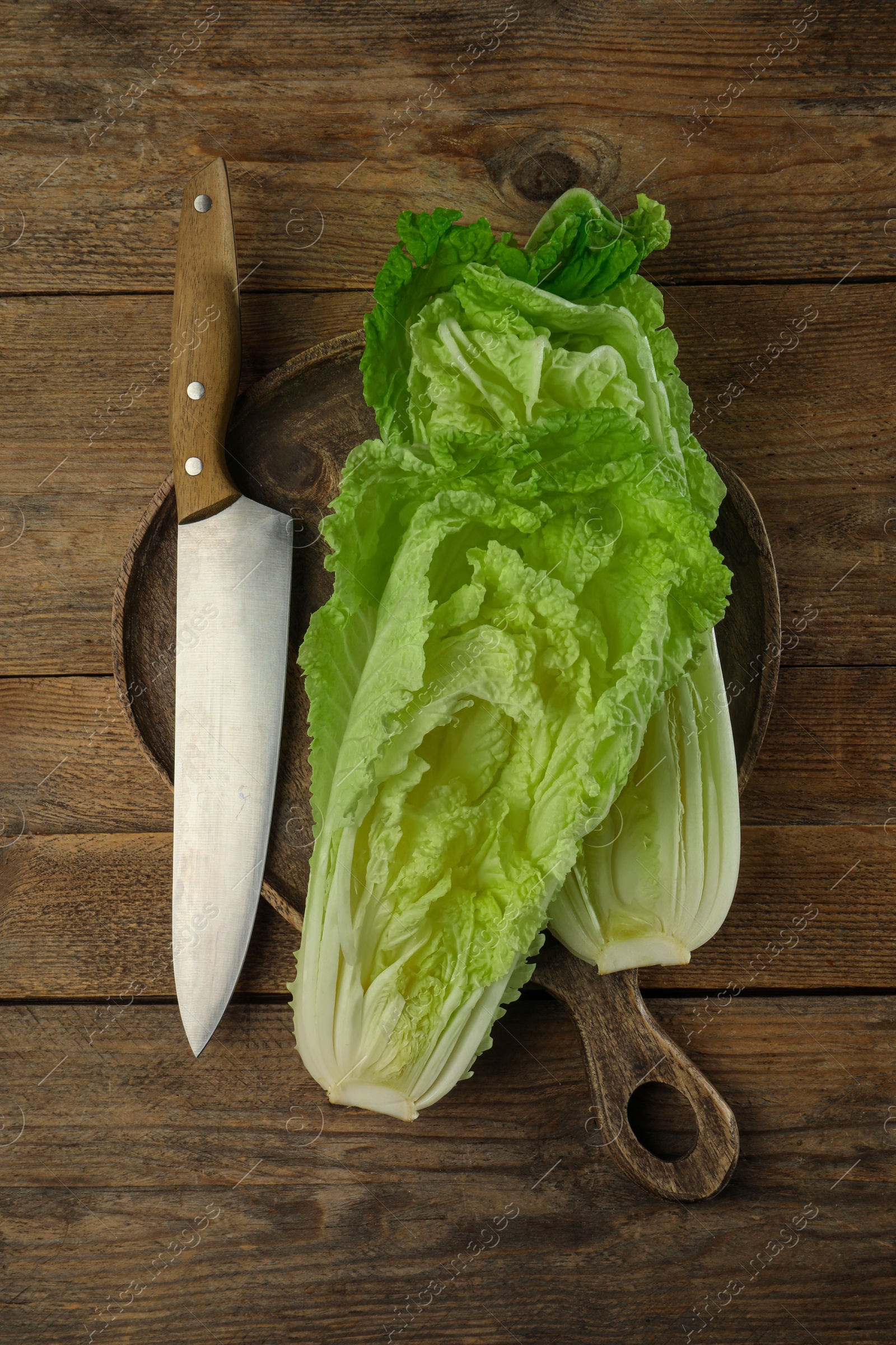 Photo of Halves of fresh ripe Chinese cabbage and knife on wooden table, flat lay