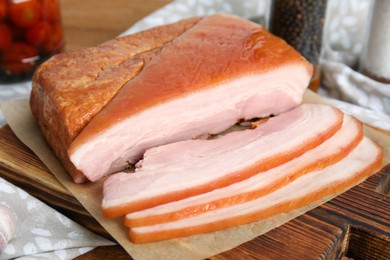 Photo of Delicious smoked bacon on wooden board, closeup