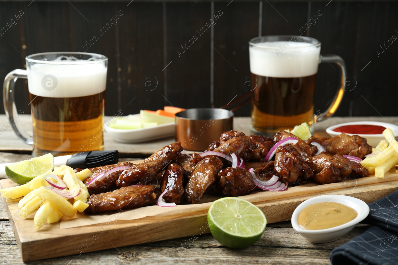 Photo of Tasty roasted chicken wings served with beer on wooden table