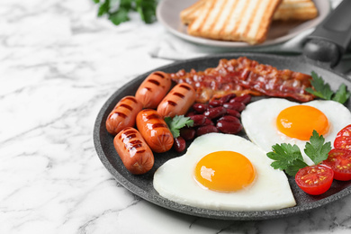 Delicious breakfast with heart shaped fried eggs and  sausages on white marble table, closeup
