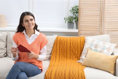Photo of Young woman with greeting card in living room