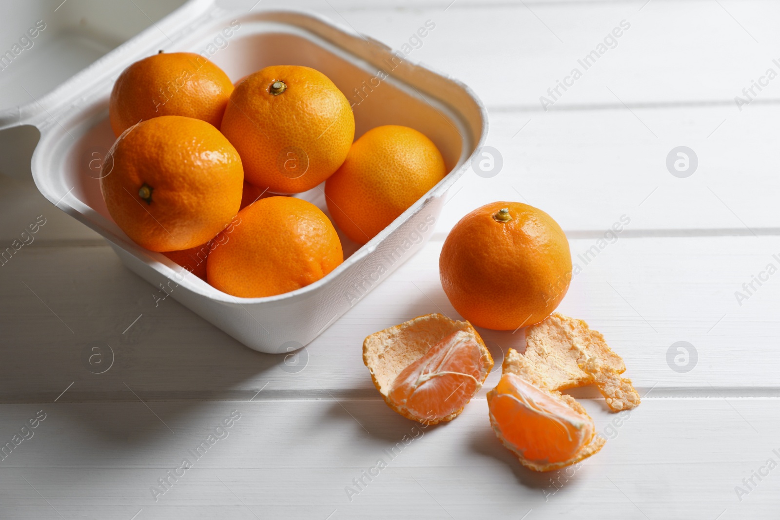 Photo of Paper box with fresh ripe tangerines on white wooden table