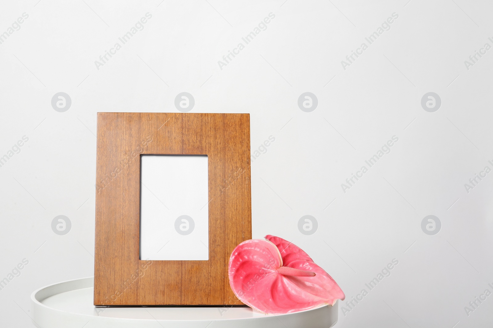 Photo of Blank frame and flower on table against white background. Mock up for design