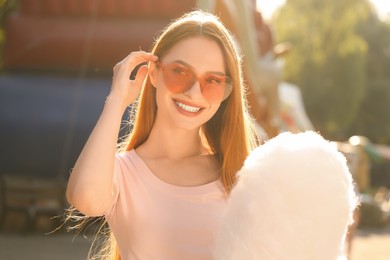 Photo of Portrait of happy woman with cotton candy outdoors on sunny day