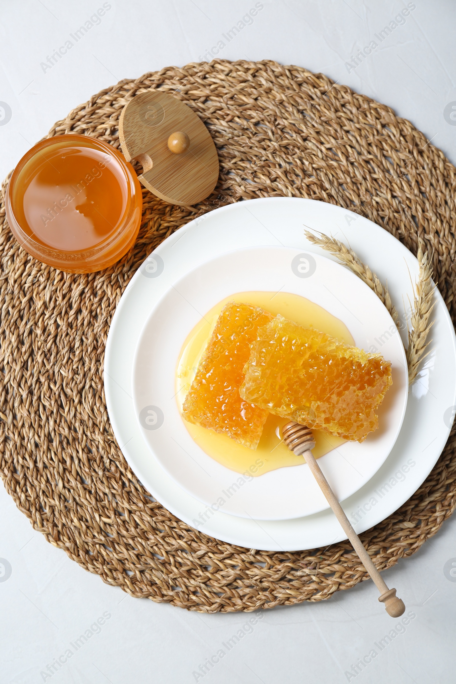 Photo of Natural honeycombs with tasty honey and dipper on white table, top view