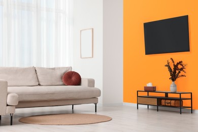 Photo of Stylish sofa near orange wall in room. Interior design